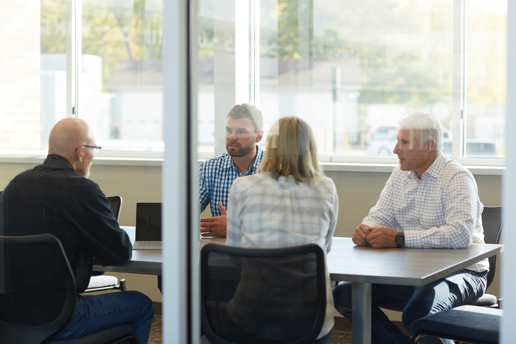 Four employees in glass wall conference room in meeting